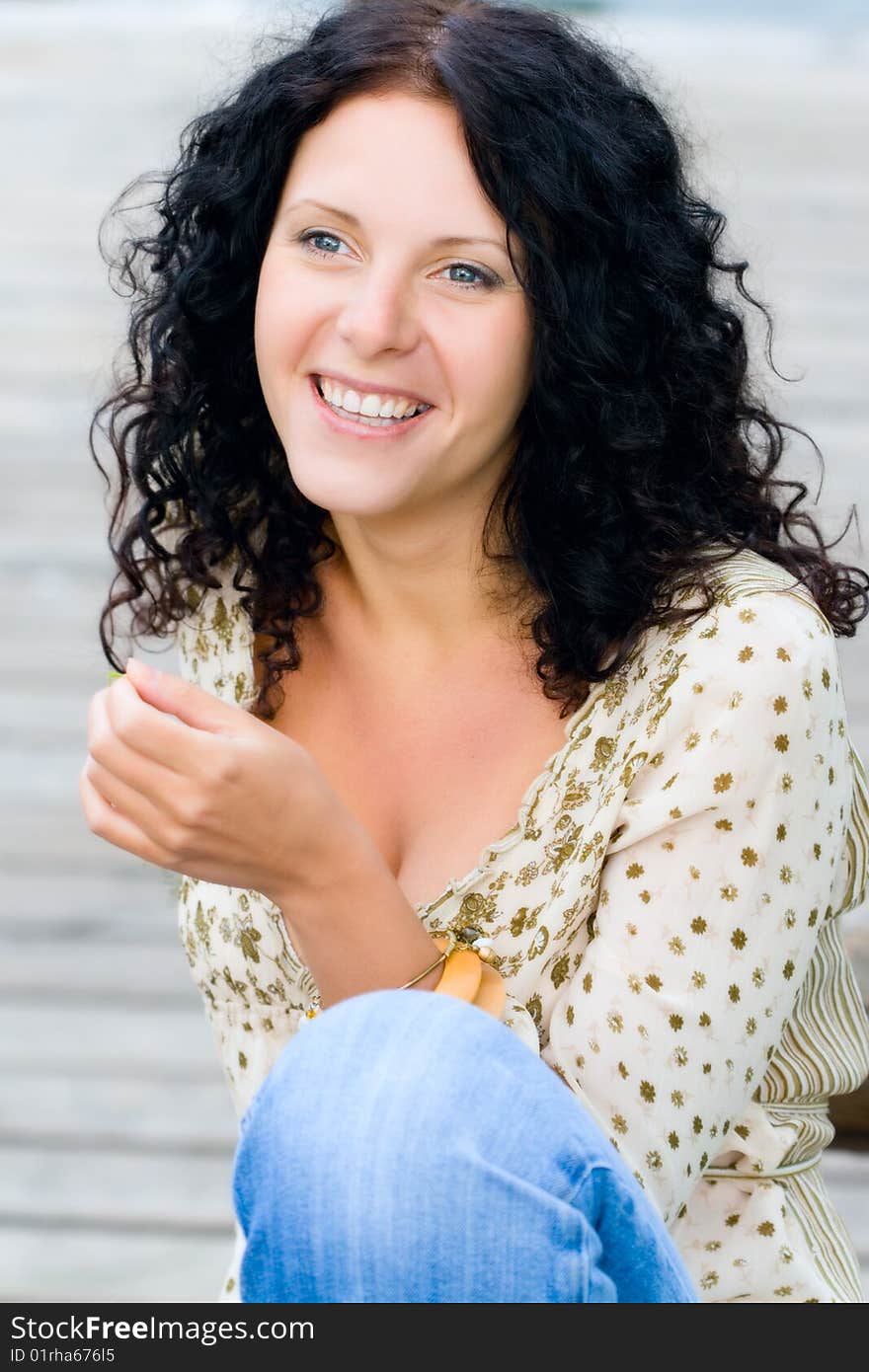 Beautiful happy brunet woman sitting on wooden floor