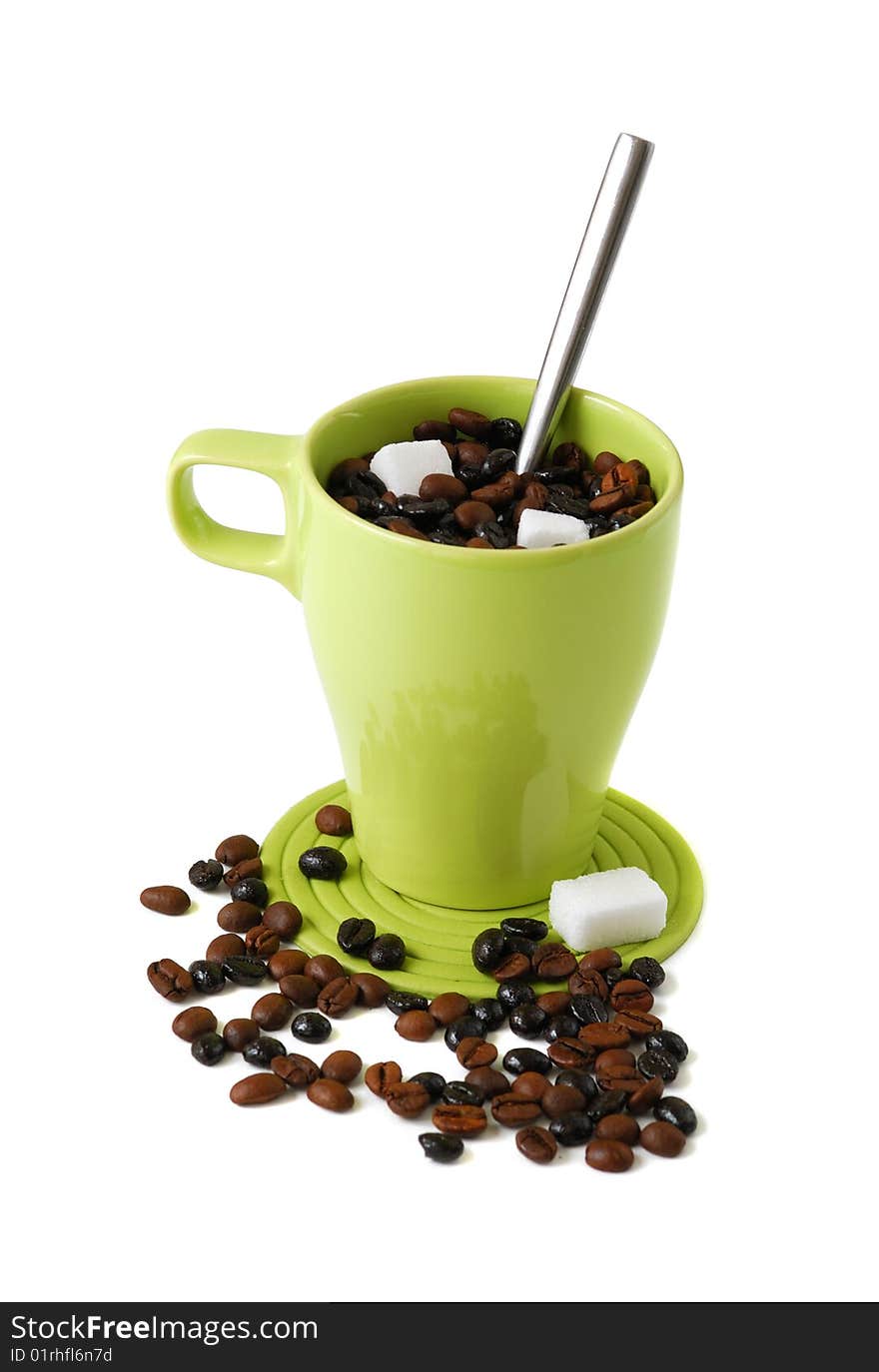 Green mug filll with with coffee beans a spoon a some sugar cubes. Green mug filll with with coffee beans a spoon a some sugar cubes