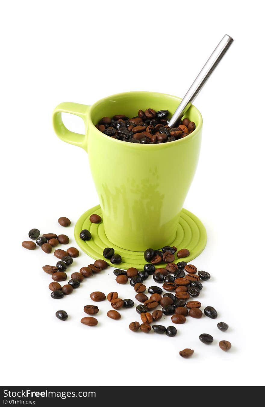 Green mug filled with coffee beans and a spoon. Green mug filled with coffee beans and a spoon