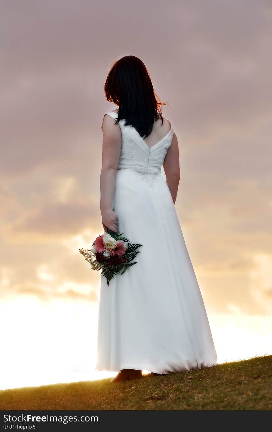 Bride standing on a hill during sunset