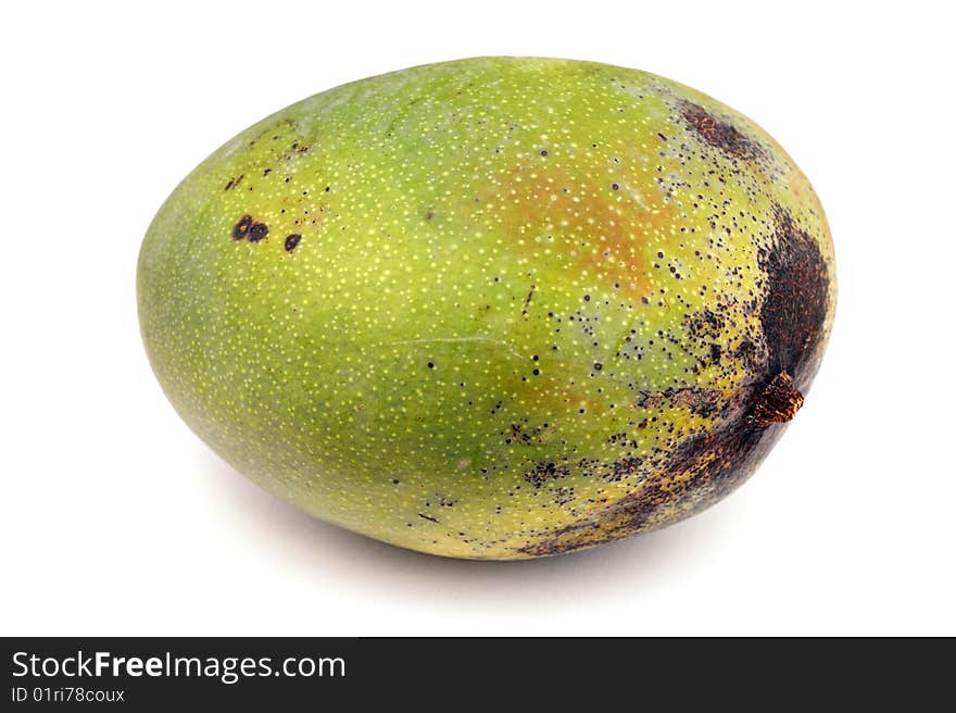 A large green uncut mango fruit on white surface. A large green uncut mango fruit on white surface