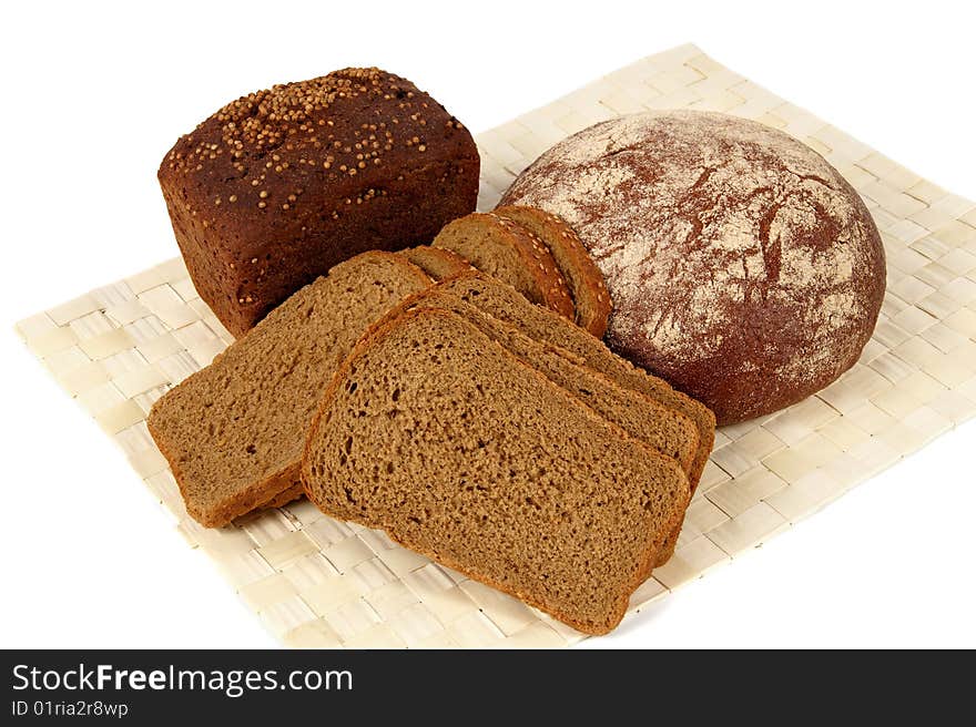 There are three types of rye bread in the picture. One loaf of bread that is on the left is covered by coriander. There are three types of rye bread in the picture. One loaf of bread that is on the left is covered by coriander.