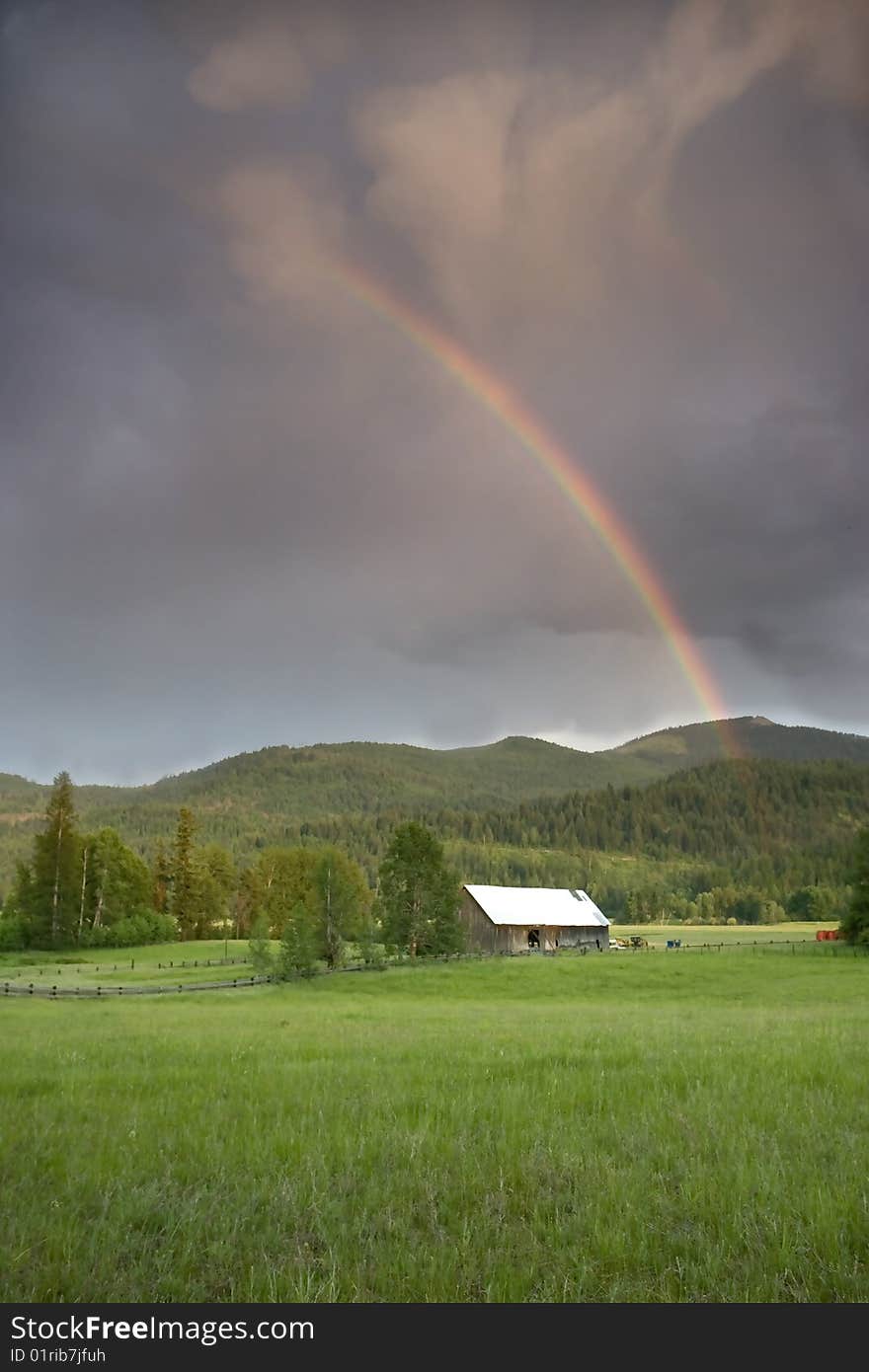 Rainbow over a barn in a field.