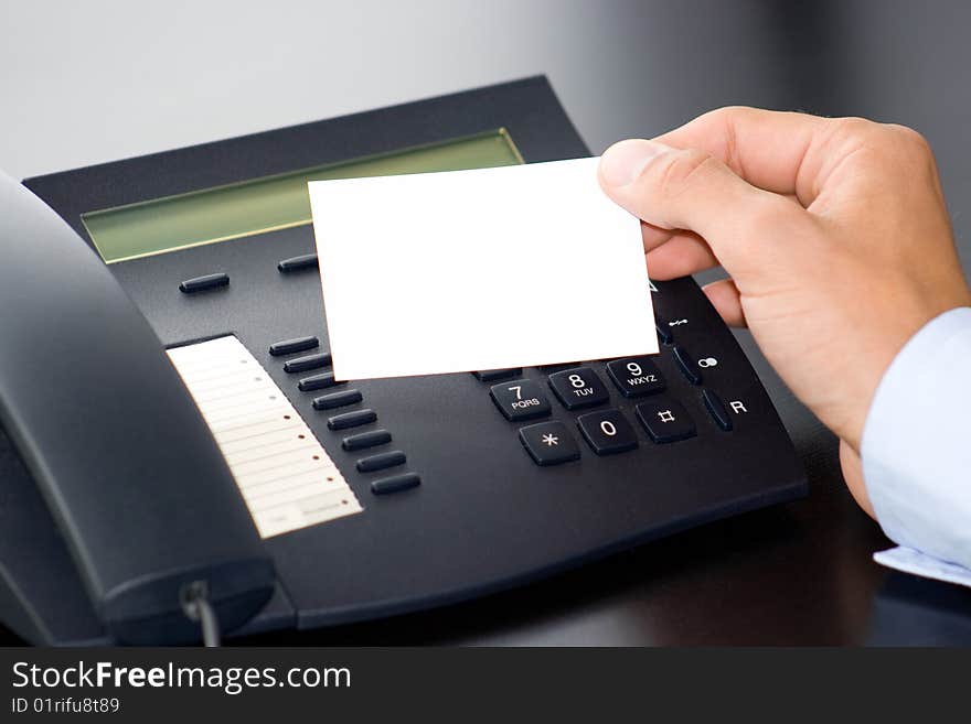 Hand with white card in front of a computer keyboard. Hand with white card in front of a computer keyboard