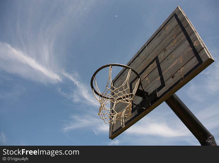 Old worn-out basketball board in the cloudy blue sky. Old worn-out basketball board in the cloudy blue sky