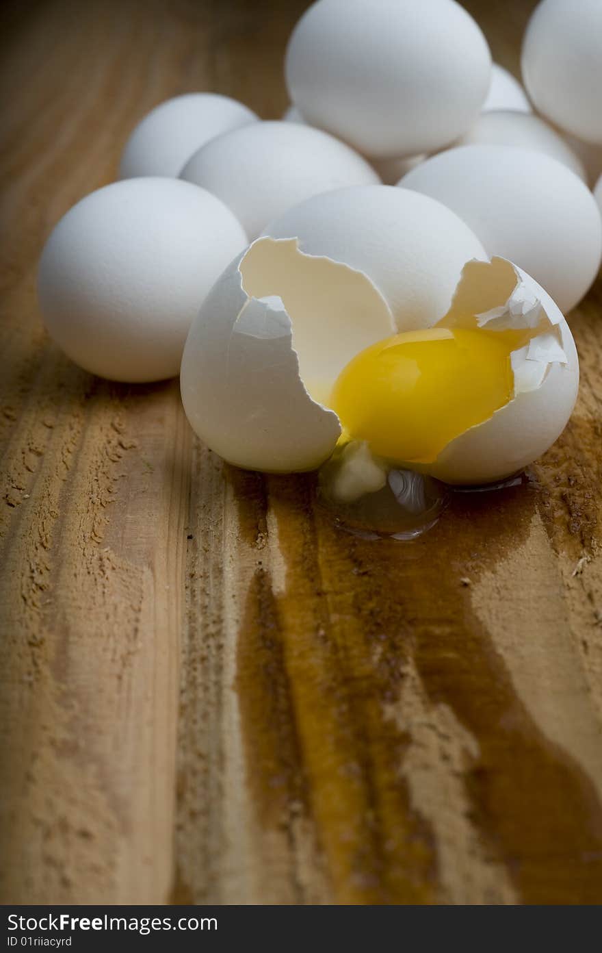 Cracked egg in front of pile of eggs.