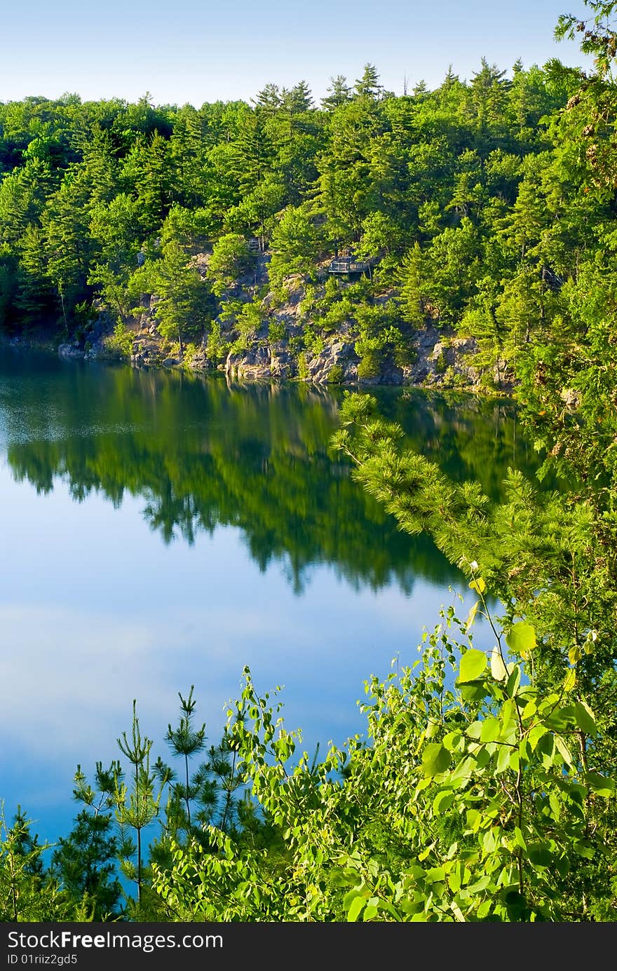 Calm, still waters of Pink lake - an extremely rare meromictic lake - in the Pink Lake Conservation Area of Gatineau Park. Calm, still waters of Pink lake - an extremely rare meromictic lake - in the Pink Lake Conservation Area of Gatineau Park.