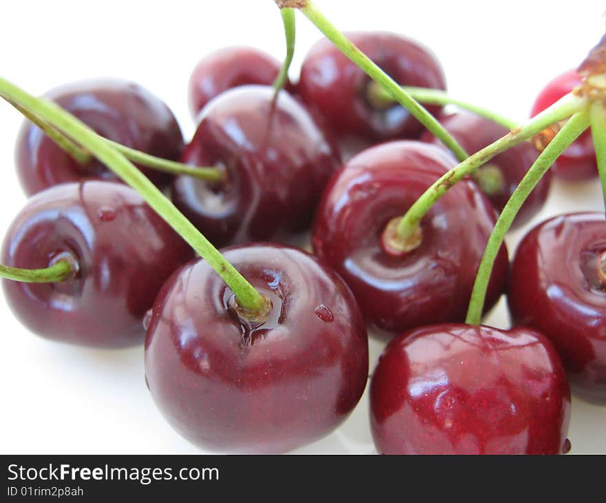 Closeup of red shiny cherries on white background.