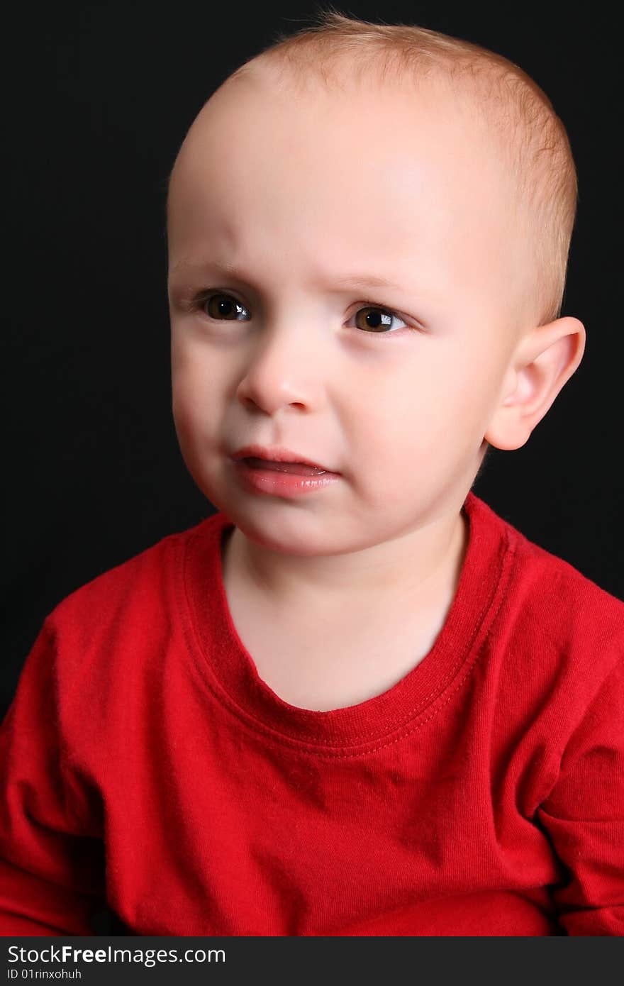 Cute toddler wearing a red shirt with a frown