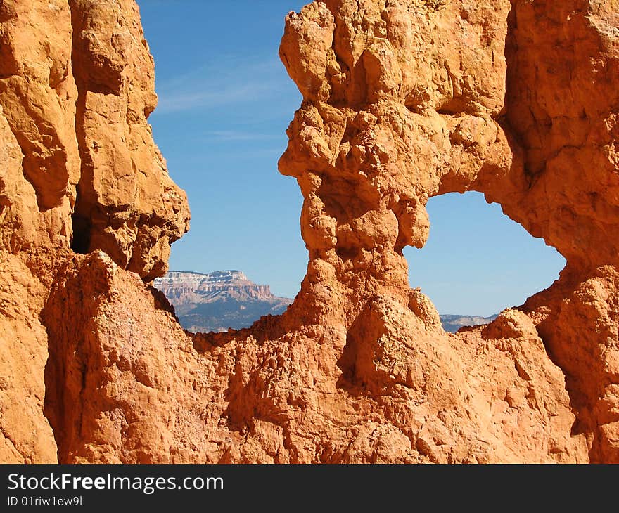 Mountains framed by the holes in the multicoloured Hoodoos at Bryce Canyon. Mountains framed by the holes in the multicoloured Hoodoos at Bryce Canyon