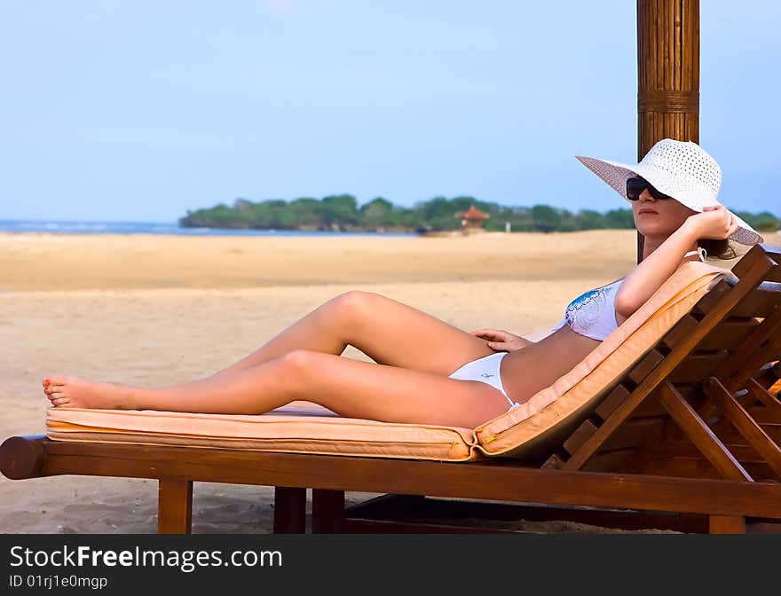 Brunnette girl in white hat lying on the beach chaise longue. Brunnette girl in white hat lying on the beach chaise longue