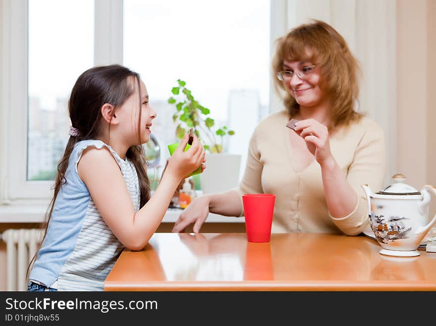 Mother and daughter drink tea behind a table