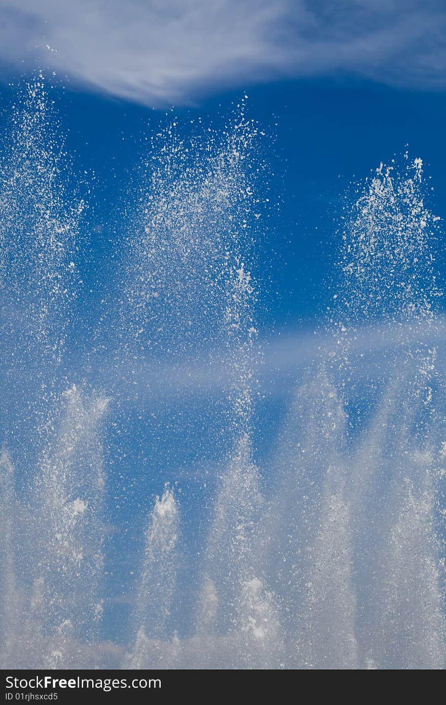 Splashes of water against the blue sky with clouds