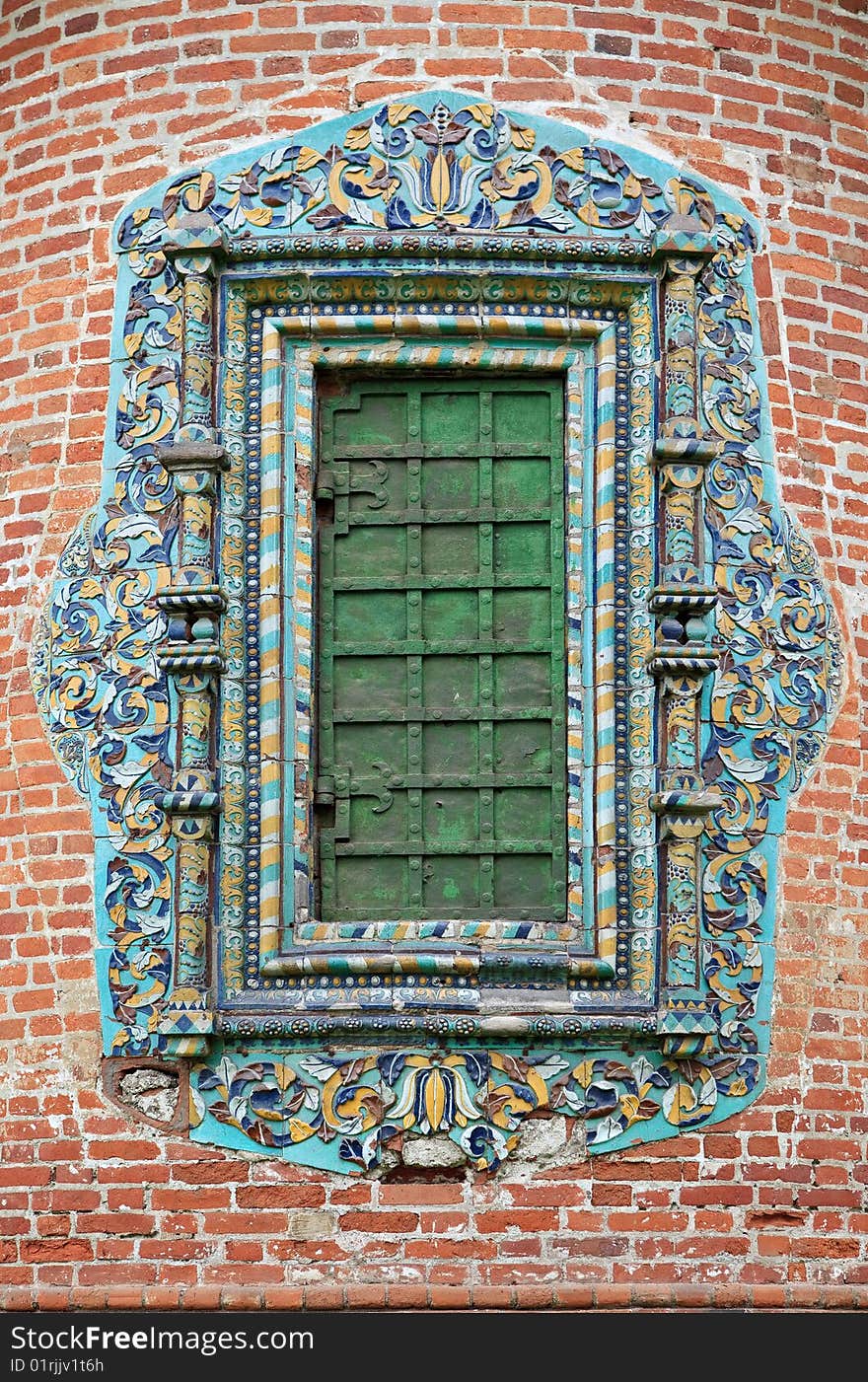 Old ornate window with heavy metal shutter on brick wall. Glazed tile it was traditionally used for an ornament exterior rich Russian churches. XVII century. Old ornate window with heavy metal shutter on brick wall. Glazed tile it was traditionally used for an ornament exterior rich Russian churches. XVII century.