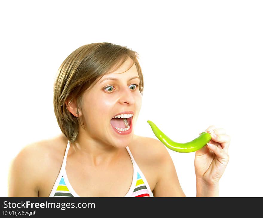 Portrait of a young cute Caucasian blond girl with a nice colorful striped summer dress who is going crazy and she is holding a fresh green chilly pepper in her hand. Isolated on white. Portrait of a young cute Caucasian blond girl with a nice colorful striped summer dress who is going crazy and she is holding a fresh green chilly pepper in her hand. Isolated on white.