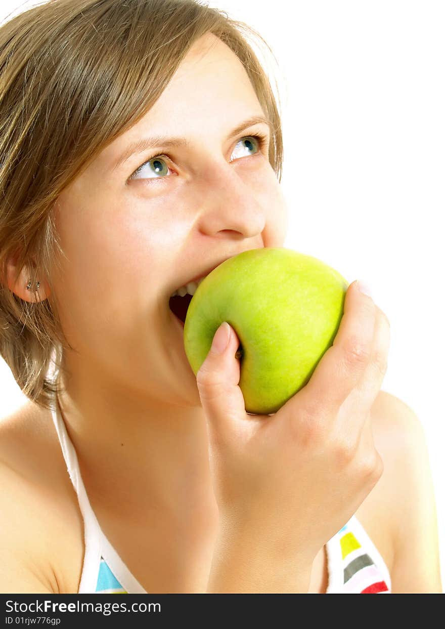 Portrait of a cute Caucasian blond girl with a nice colorful striped dress who is smiling and she is biting a fresh green apple. Isolated on white.