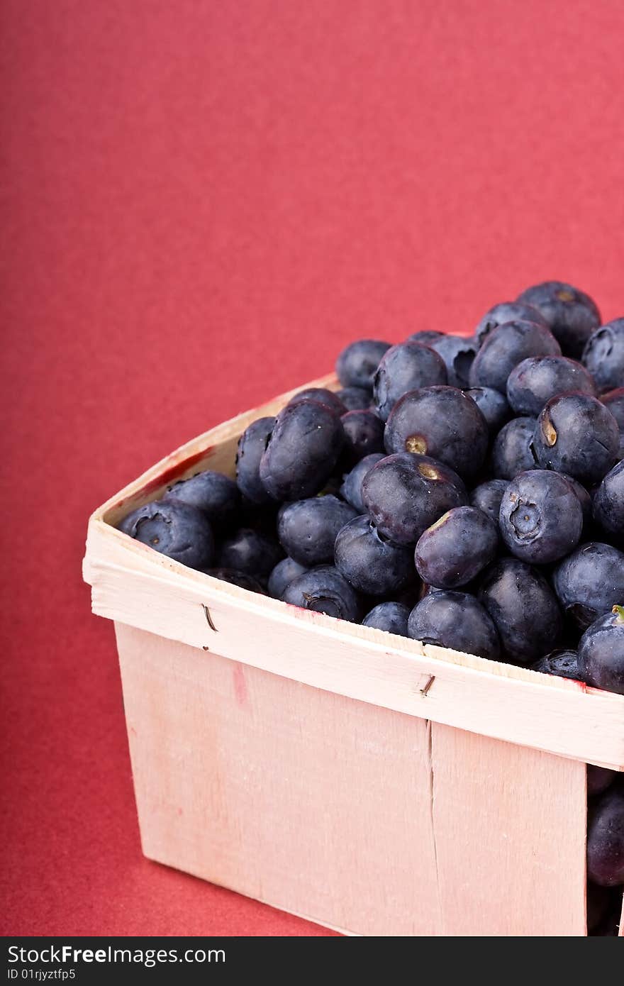 Wooden quart of blueberries on a red background. Wooden quart of blueberries on a red background