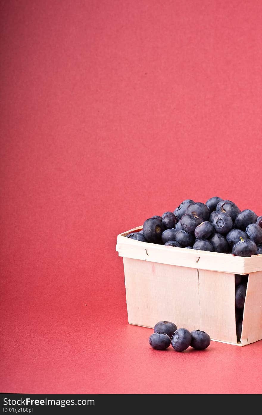 Wooden quart of blueberries on a red background. Wooden quart of blueberries on a red background