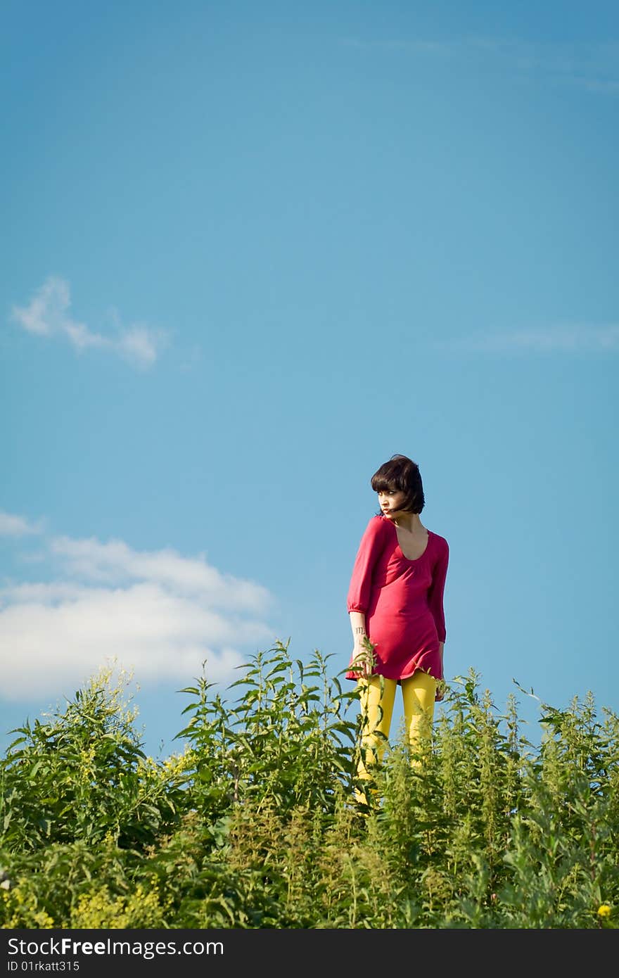 Girl goes on the grass against the background of blue sky. Girl goes on the grass against the background of blue sky.