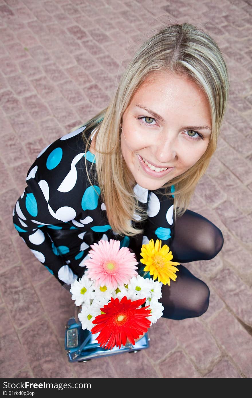 Beautiful girl with a bunch of flowers sits on a stone roadway. Beautiful girl with a bunch of flowers sits on a stone roadway