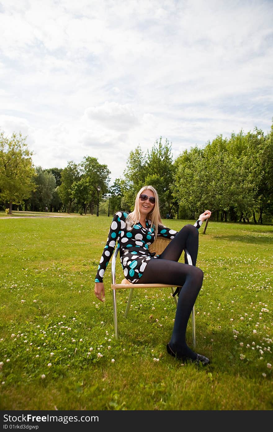 Girl sits on a chair against the nature