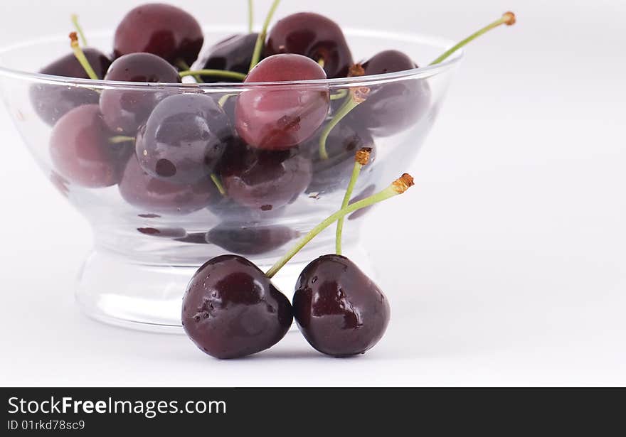 Ripe sweet cherry in a glass on a white background