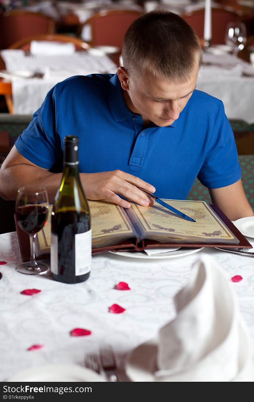 The man in cafe and chooses meal under the menu