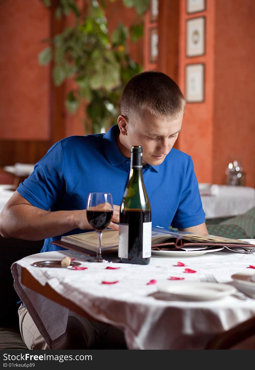 The man in cafe and chooses meal under the menu