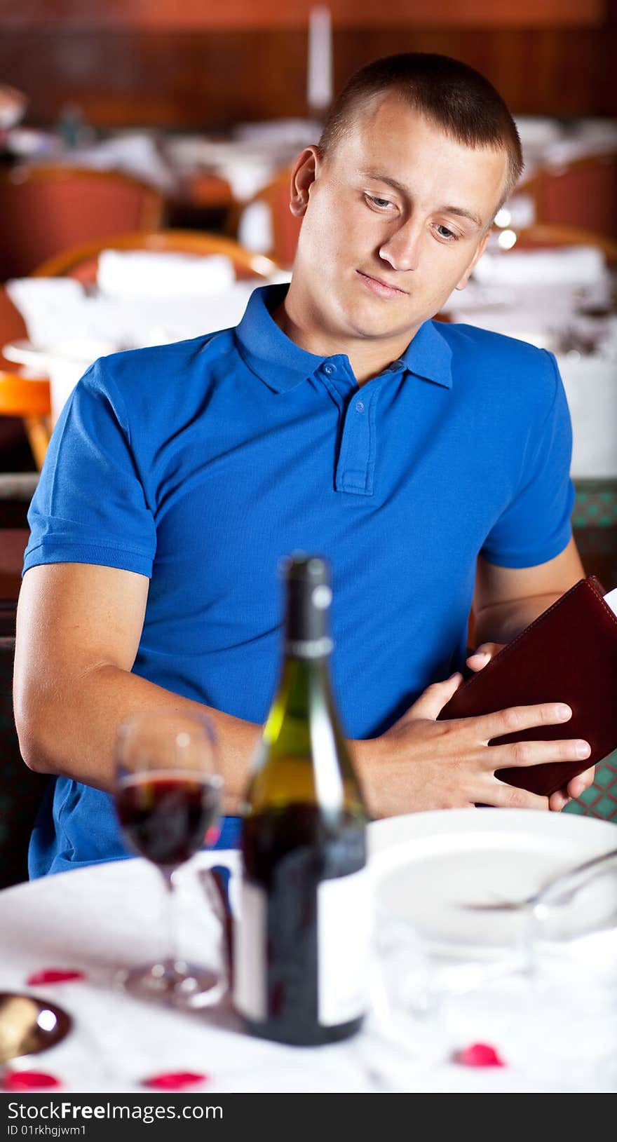 The man  looks at a glass with red wine in cafe