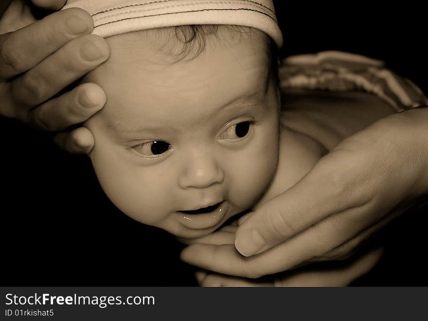 Toned portrait of the kid training to hold a head by means of mum's hands. Toned portrait of the kid training to hold a head by means of mum's hands