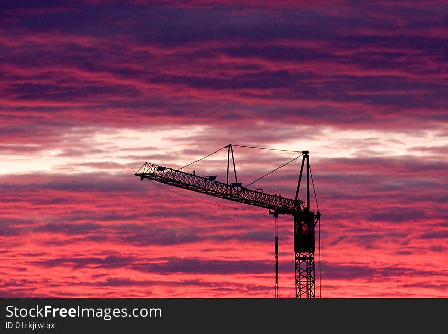 A construction crane in front of a dramatic sunset, blue and red sky. A construction crane in front of a dramatic sunset, blue and red sky