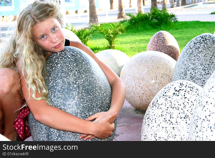 Pretty blonde girl hugging stone eggs.