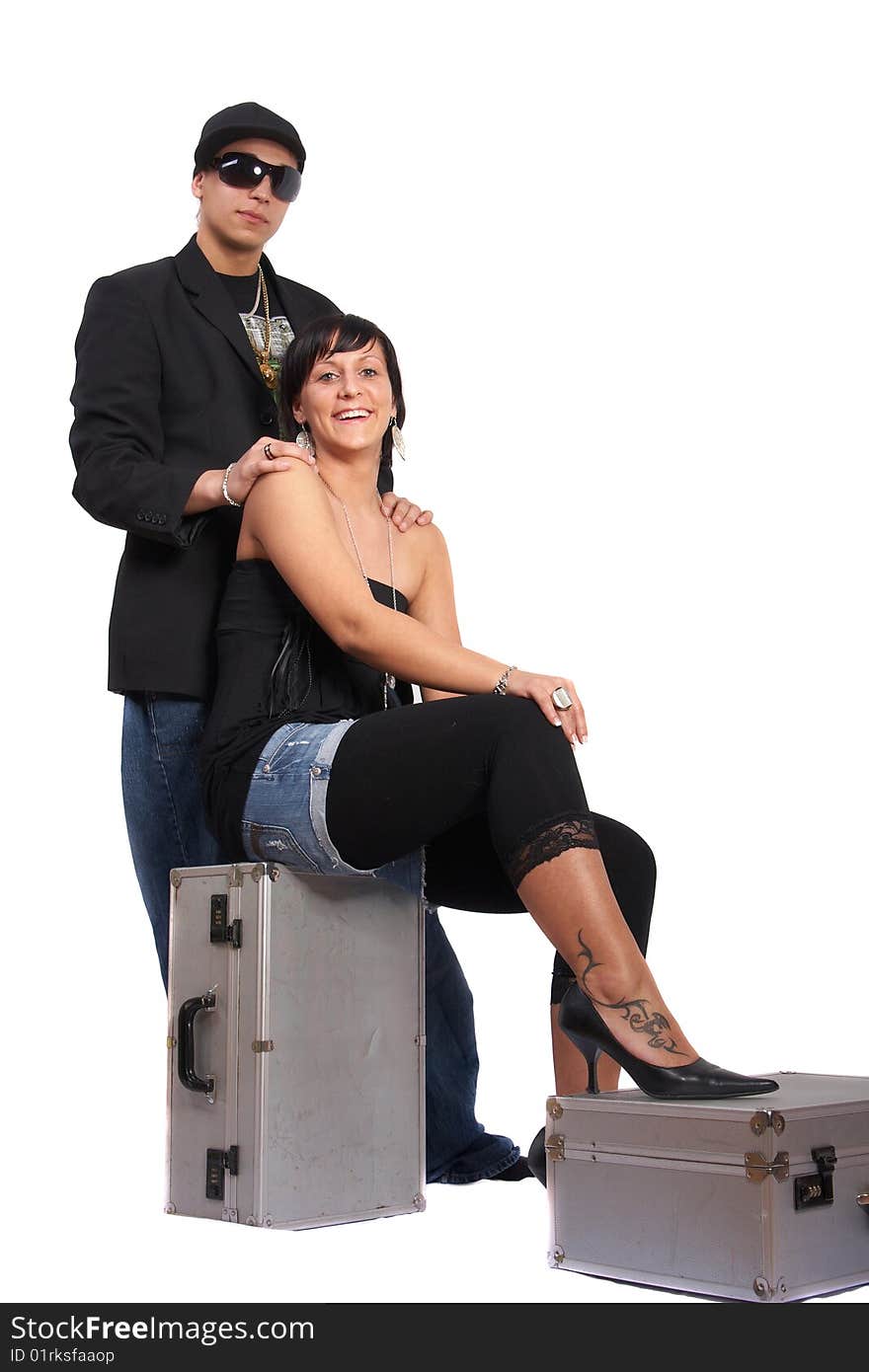 Young stylish couple isolated over white. She is sitting on dj cases. Young stylish couple isolated over white. She is sitting on dj cases.