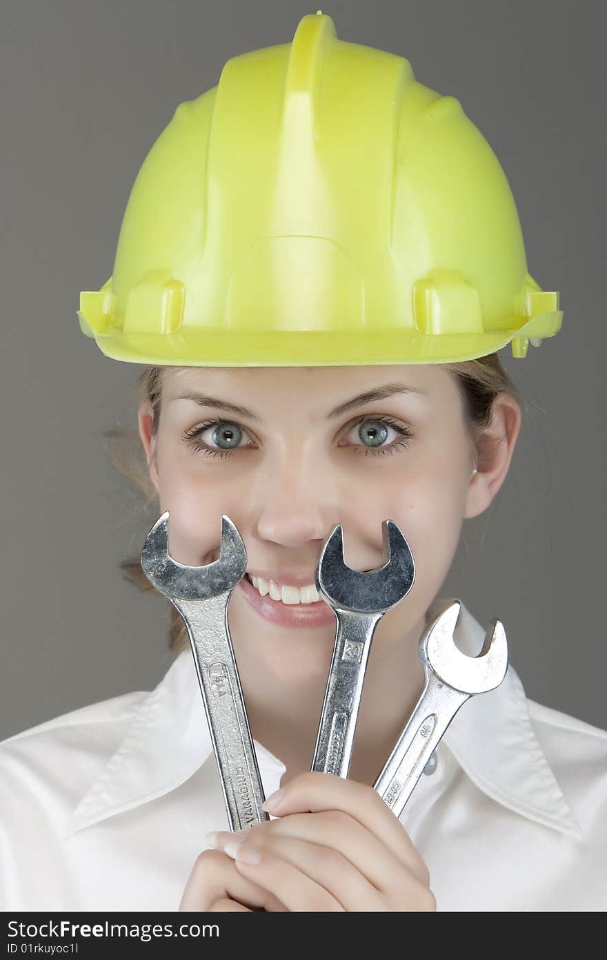 Pretty girl with helmet and wrench over white background