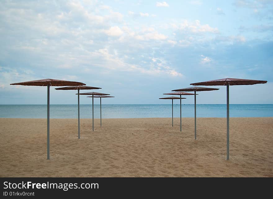 Symmetrical rows of the wooden sun covers at the seafront. Symmetrical rows of the wooden sun covers at the seafront