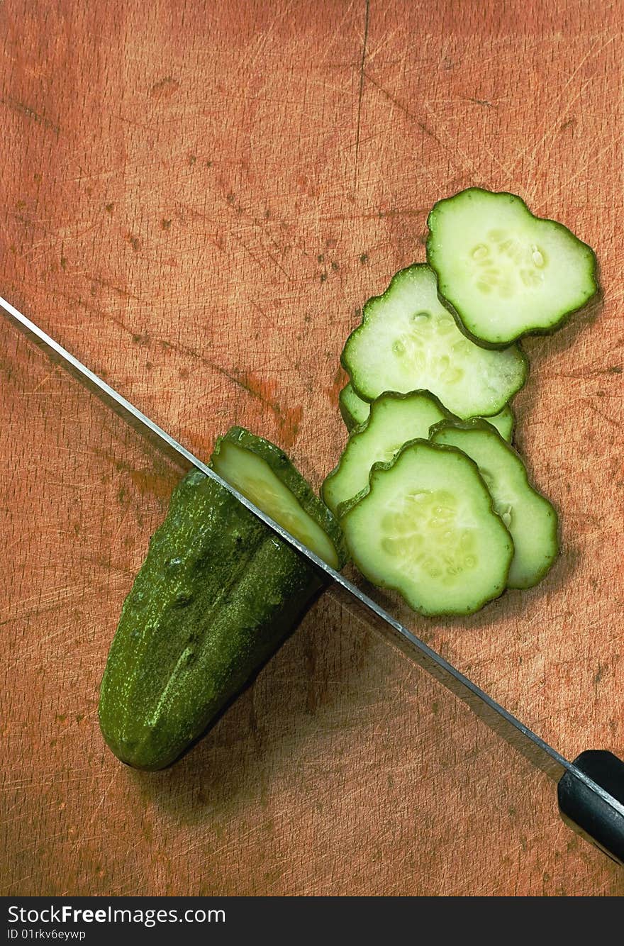 Cucumber and kitchen knife on wood table with selective focus. Cucumber and kitchen knife on wood table with selective focus