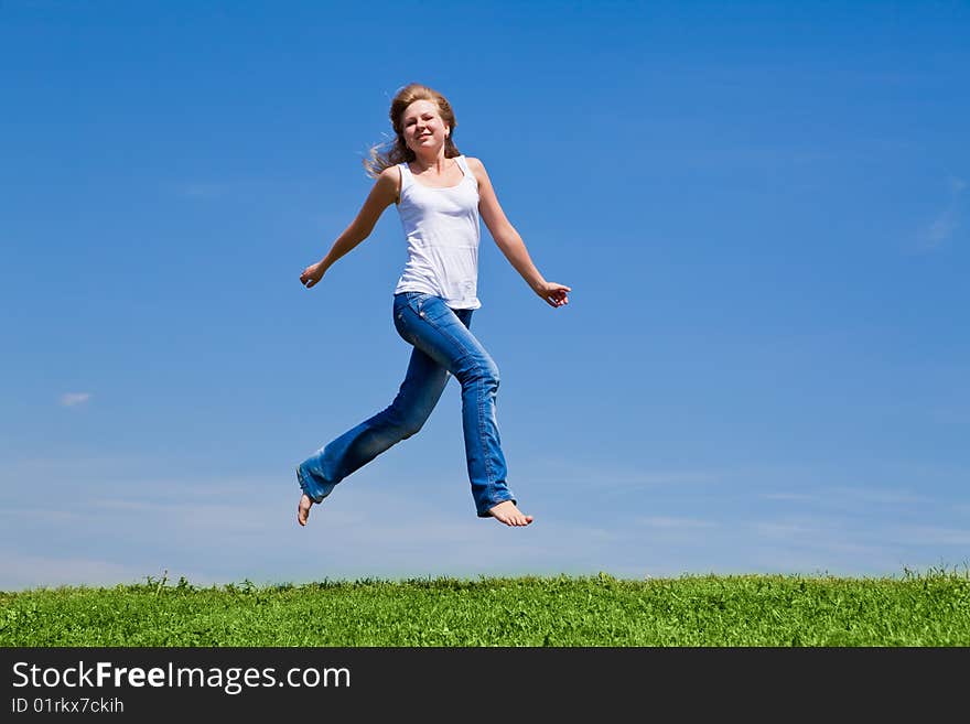 Girl run on a green grass against the blue sky. Girl run on a green grass against the blue sky