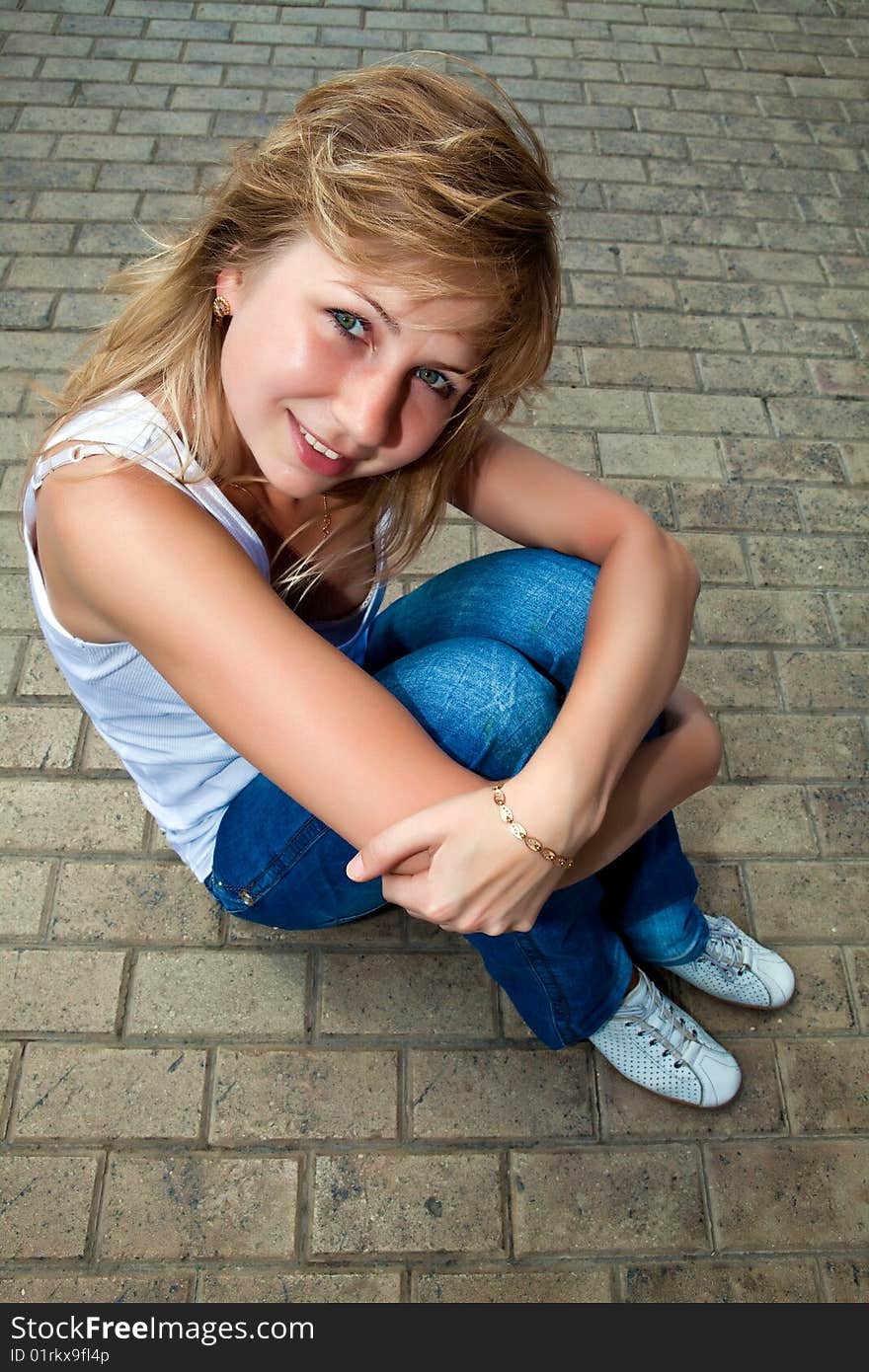 Beautiful girl sits on a stone roadway. Beautiful girl sits on a stone roadway