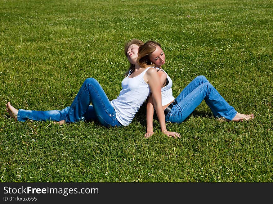 Two girls have a rest on a green grass. Two girls have a rest on a green grass