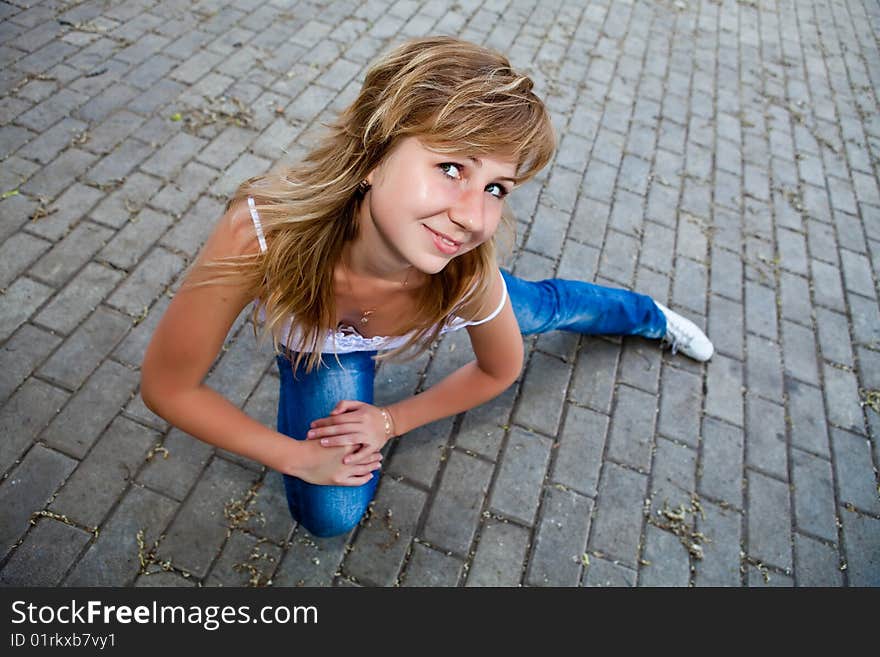 Beautiful girl sits on a stone roadway. Beautiful girl sits on a stone roadway