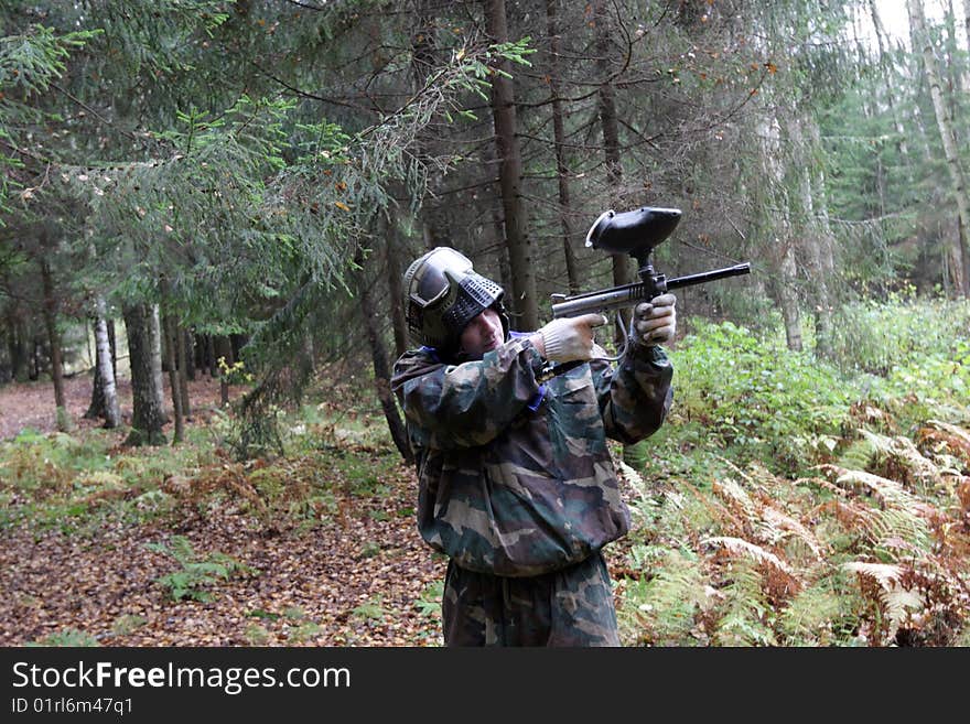 The man plays in paintball in a coniferous forest