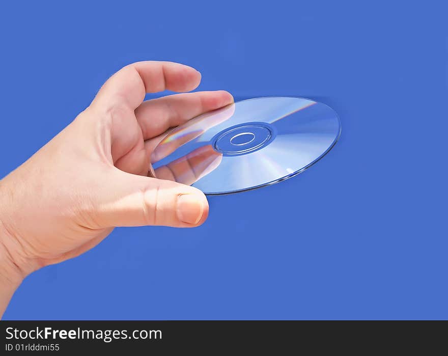 A hand holding a CD or DVD media against a blue background. A hand holding a CD or DVD media against a blue background