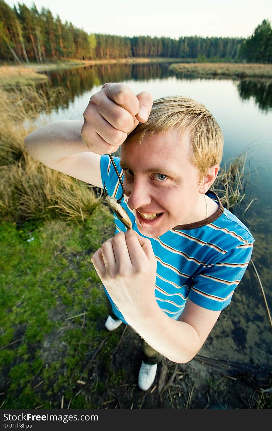 A guy on a river bank demonstrating  his catch. A guy on a river bank demonstrating  his catch