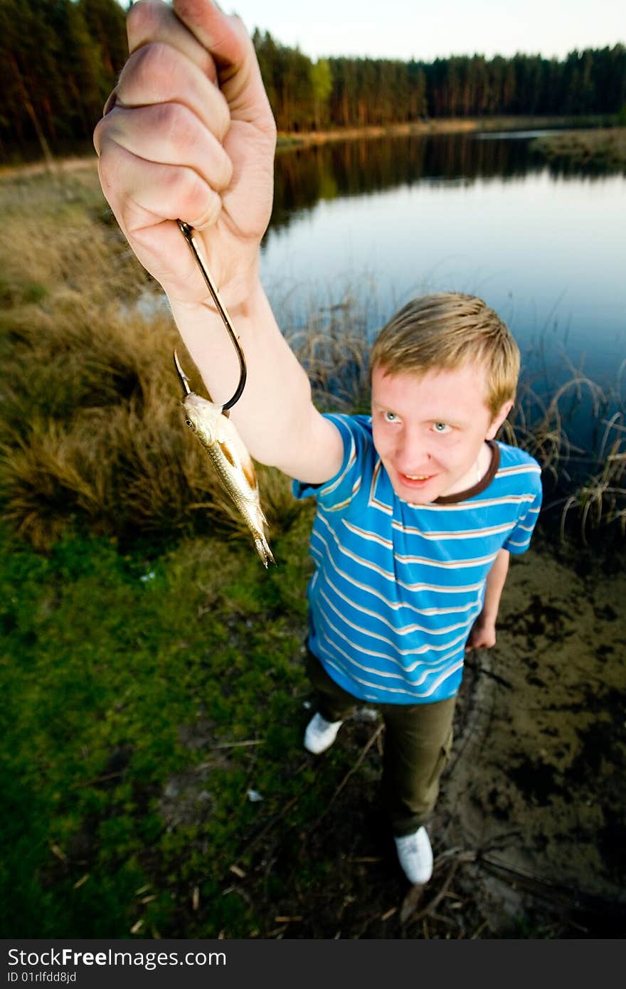 A cute guy showing off a crucian he has just caught. A cute guy showing off a crucian he has just caught