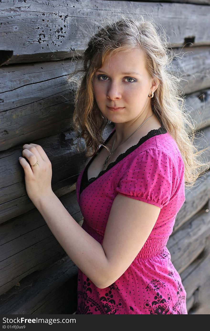 Young girl in front of wooden log hut