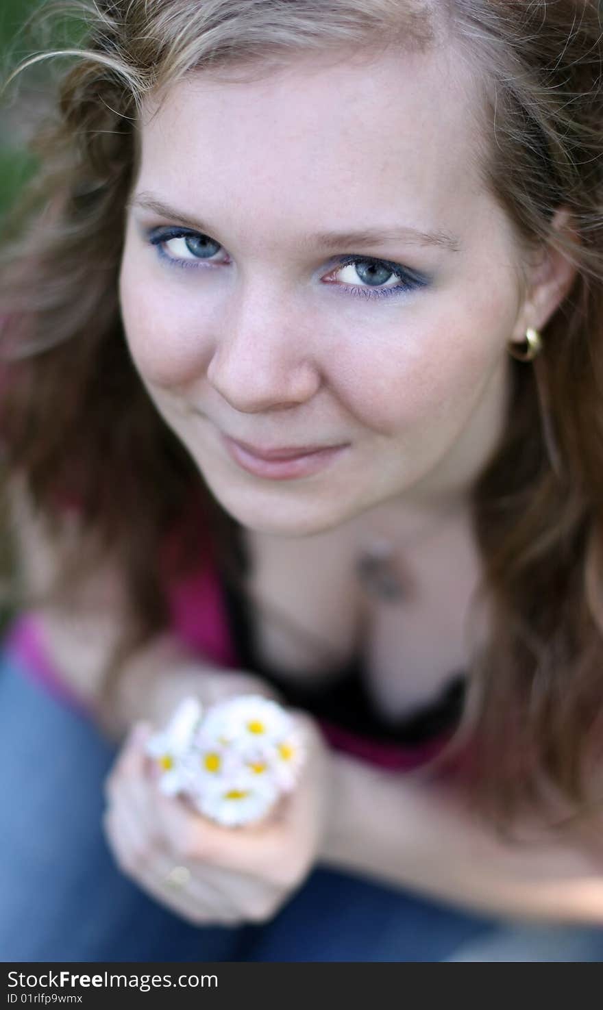 Smiling girl with marguerite, looking up