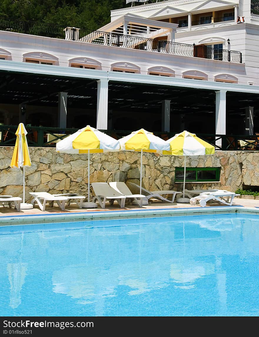 Sunbeds and umbrellas near resort's pool. Sunbeds and umbrellas near resort's pool