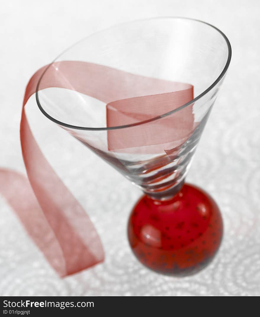 Red ribbon in glass cup on white plex