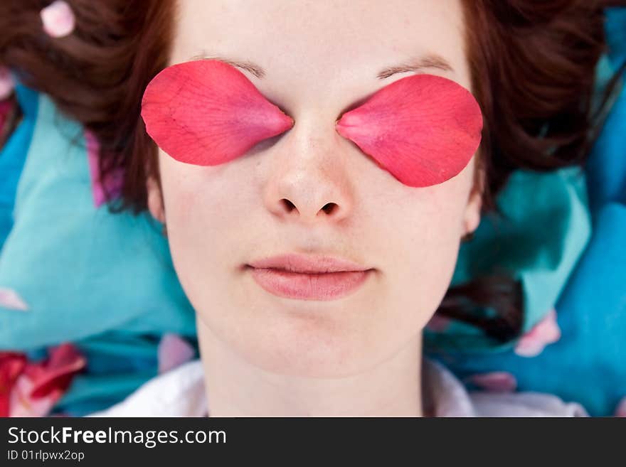 Young woman with pink petals on her eyes