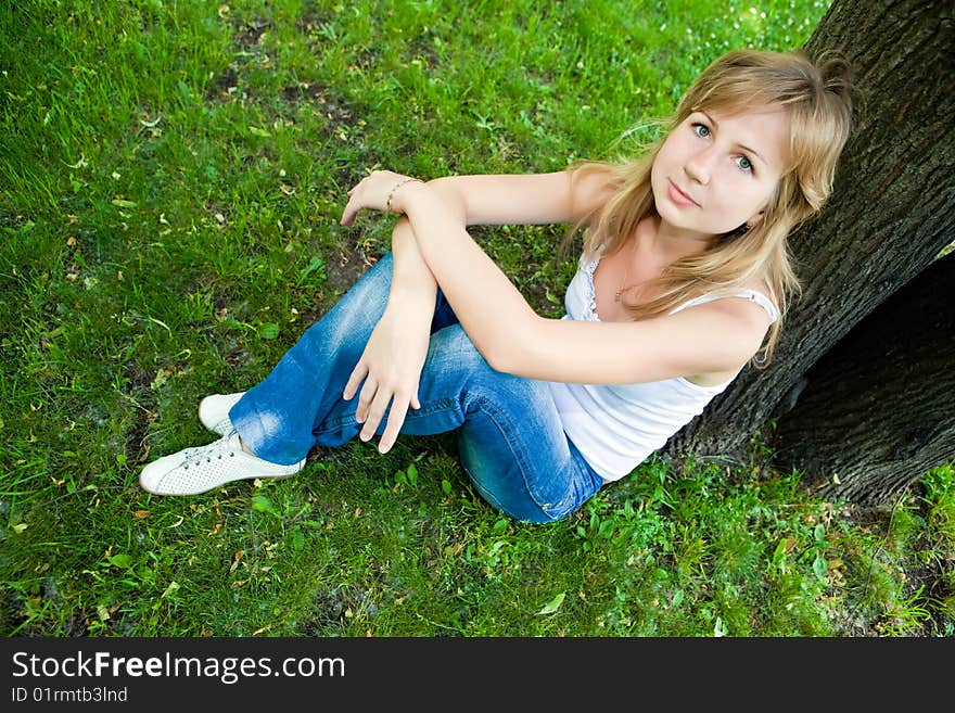 Beautiful young woman sits on a green grass. Beautiful young woman sits on a green grass